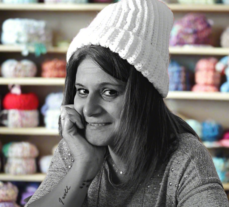 Mirna Fourel , La créatrice de Fenicrochet Femme souriante portant un bonnet blanc, devant des pelotes de laine colorées.