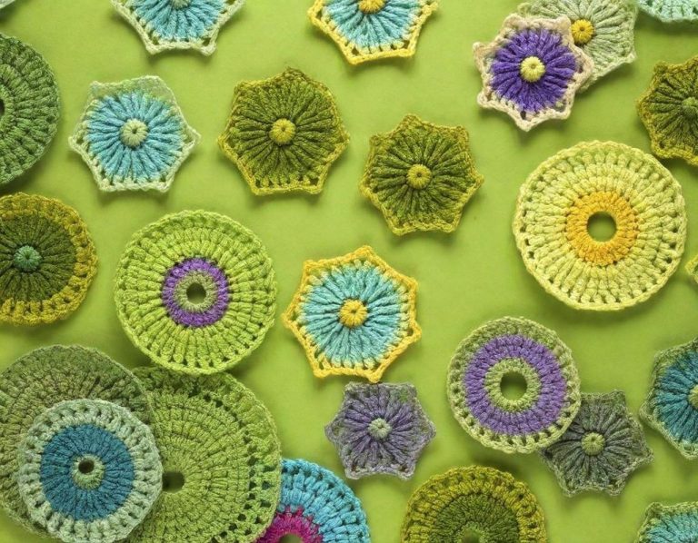 Motifs en crochet colorés sur un fond vert, présentant diverses formes géométriques.