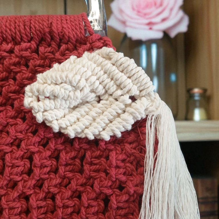 Sac en tricot rouge avec un appliqué en forme de feuille écrue et un pompon. FeniCrochet 