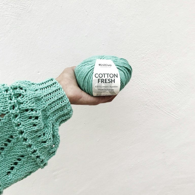 Avec FeniCrochet, L'artisanat est ecologique Pelote de fil en coton vert, tenue à la main, avec une étiquette visible.